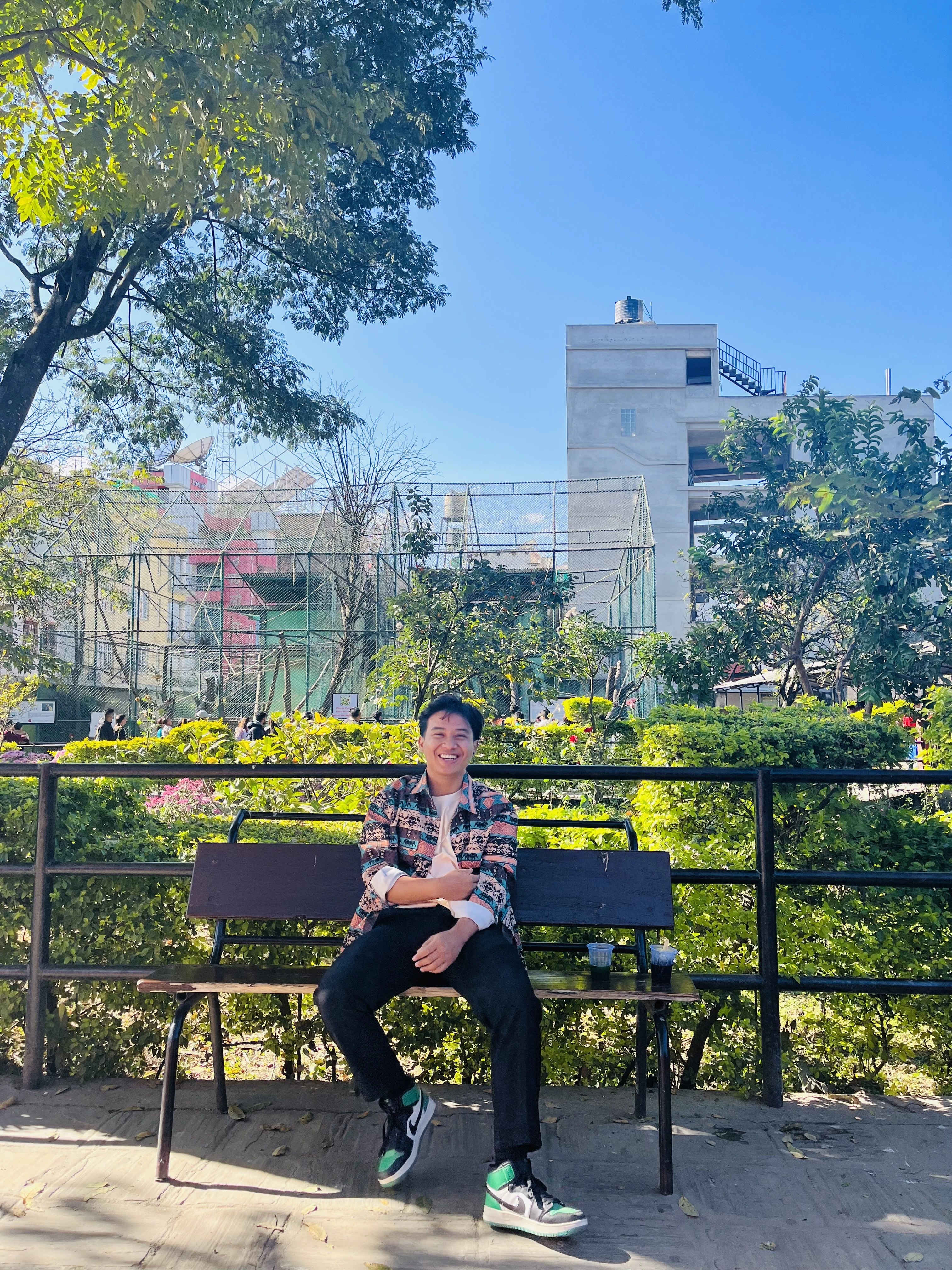 Aashish Thakuri smiling on a garden bench in the sunshine