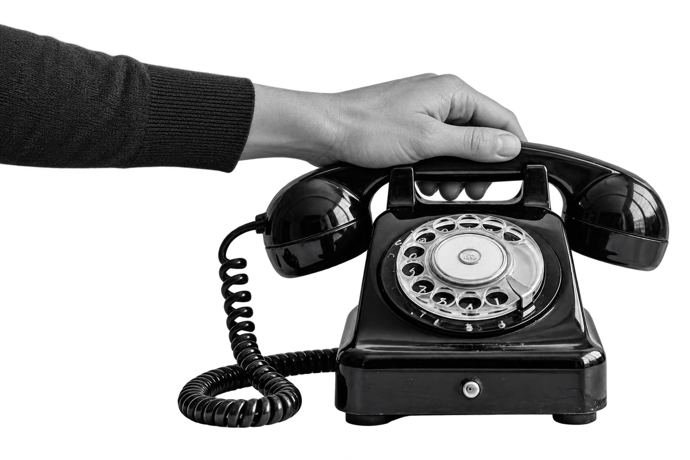 A natural hand gripping a horizontal receiver seated on both cradle supports of a vintage rotary telephone, with its cord connected